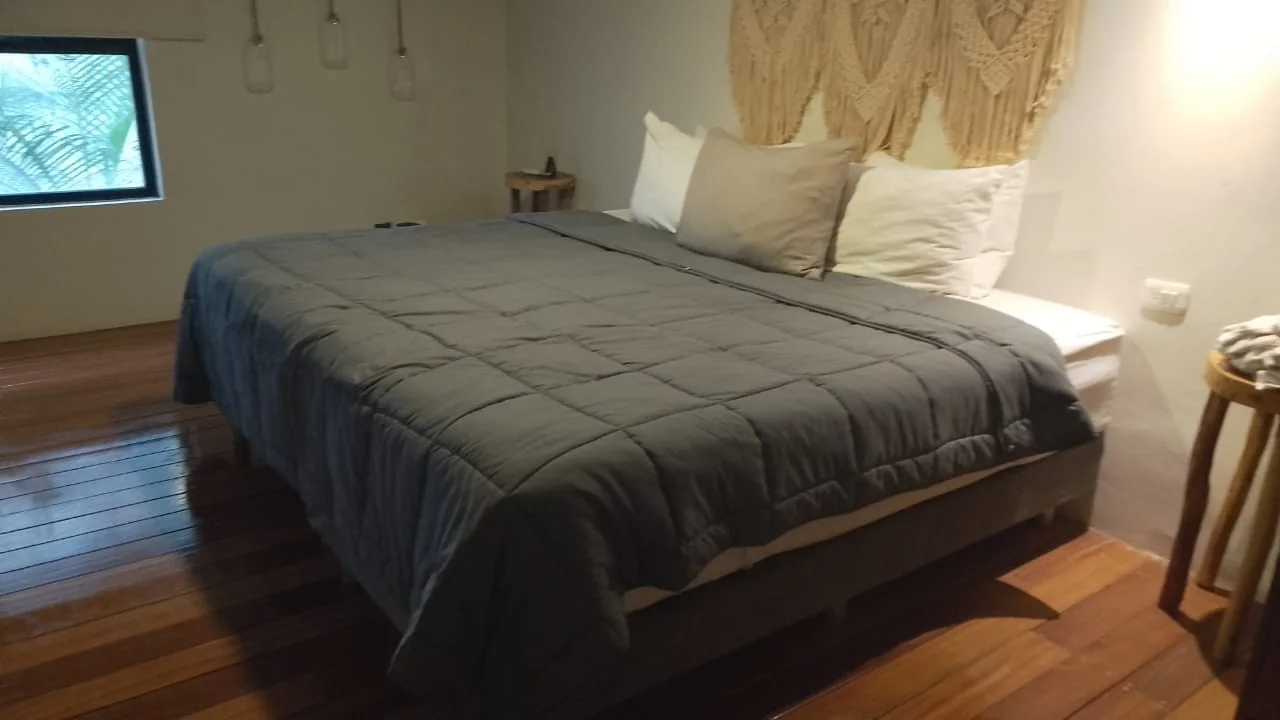 Recámara con piso de madera y cabecera de macramé en Harmony, Casa de los Sueños, Tulum
